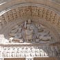 Le tympan de Saint-Trophime reprend le thme biblique du ttramorphe voquant la vision d'zchiel ou l'Apocalypse de saint Jean, symbole ensuite des quatre vanglistes; il montre un Christ triomphant et justicier, assis, tenant sur ses genoux la bible et bnissant avec ses deux doigts de sa main droite leve. Il est entour par les symboles classiques des quatre vanglistes : un lion ail pour saint Marc, un ange (ou un homme ail) pour saint Mathieu, un aigle pour saint Jean et un taureau ail pour saint Luc. Les deux vanglistes figurant au bas du tympan Marc et Luc, qui  la diffrence de Mathieu et Jean n'ont pas connu le Christ, ne regardent pas le fils de Dieu. Sur cette frise, galement en calcaire oolithique, sont figurs sous le tympan les douze aptres assis et tenant un livre sur les genoux. Ils sont les tmoins de la rsurrection du Christ. 