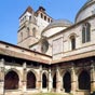 Cahors : Le clotre de la cathdrale Saint-Etienne - Une porte,  droite du chur, permet d'accder au clotre gothique flamboyant qui fut difi en 1504 par l'vque Antoine de Luzech. Les sculptures profanes reprsentant des coquillards, des buveurs, des musiciens, un architecte au travail, ont peut-tre t copies sur celles de Cadouin. On peut voir sur une pierre carre se disputer deux plerins, l'un tenant une coquille. Au nord-ouest, la petite Vierge sous son dais de coquilles, est une des rares reprsentations religieuses pargnes par les protestants. Sur le ct ouest, la chapelle Saint-Gaubert, dont la vote est orne de peintures de la Renaissance italienne et les murs, de fresques du XVe sicle, reprsentant l'enfer et le Jugement dernier, contient un muse d'art sacr. Des vtements sacerdotaux et les portraits de 93 vques de Cahors y sont exposs. Curiosit : la surface de la cour intrieure est strictement gale  la surface de la galerie qui l'entoure, illustrant ainsi la duplication du carr et le nombre racine carre de deux qui a fascin mathmaticiens et architectes depuis Babylone.