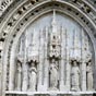 Dtail du porche d'entre de l'glise Sainte Radegonde. Le portail de style gothique flamboyant est du XVe sicle, tout comme le rare parvis qui est conserv. Il s'agit d'un parvis de justice, entour de bancs de pierre, sur lesquels sigeaient les juges ecclsiastiques, jugeant les affaires religieuses et civiles du bourg.