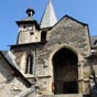 Estaing : L' glise Saint-Fleuret fut construite au XVe sicle sur l'emplacement d'un ancien prieur Saint-Fleuret qui avait t donn l'abbaye de Montsalvy par Pons tienne, vque de Rodez (1076-1085). Elle abrite maintenant, indpendamment des reliques du patron de la ville, un trs beau Christ du XVe sicle et une piet du XVIIe sicle ainsi qu'une statue de saint Jacques dans un retable dor.  l'extrieur, sur la terrasse, une croix en pierre sculpte du XVe sicle est particulirement remarquable. Entre le motif principal et le ft, on discerne  gauche un petit plerin agenouill qui semble implorer le Christ. Il a son chapeau  large bord rejet en arrire et son costume rappelle une fois de plus le souvenir du plerin de Compostelle.