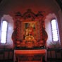 Un retable dont le frontispice est orn� d'un � Dieu tout puissant � cr�ateur du ciel et de la terre. Il repose sur deux colonnes repr�sentant les piliers de la foi, l'ancien et le nouveau testament. La vigne et les grappes de raisins qui les d�corent en repr�sentent les fruits. Sur les c�t�s, les tourbillons repr�sentent la Gen�se. Les palmes des c�t�s et au sommet les deux anges aux trompettes en chamade proclament le triomphe de la religion catholique (apostolique romaine). Comme il est d'usage le trumeau est orn� d'un tableau d�dicatoire, ici saint Blaise, �v�que et m�decin.