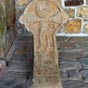 Avant de p�n�trer dans l'�glise on d�couvre, sous son grand porche en bois, une �tonnante croix disco�dale  avec un personnage sculpt�  (un Christ?) de fa�on tr�s na�ve. Sa t�te tr�s grosse et ses mains disproportionn�es font penser � certains dessins d'enfants!
