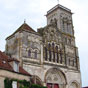 Vzelay ! Ce sommet de lart roman est un site merveilleux d'art et d'histoire. Cest sur lune des dernires collines du Morvan, dominant la valle de la Cure, que sest difie ds le 9e sicle labbaye de Vzelay puis la ville mdivale importante et florissante. Alors commence un ample mouvement de convergence vers la sainte colline, qui fait de Vzelay, pendant prs de trois sicles, lun des quatre principaux plerinages de la Chrtient, avec Jrusalem, Rome et Saint-Jacques-de-Compostelle. Vzelay devient une halte importante sur la route du plerinage de Compostelle et son histoire est marque galement par le grand vnement de 1146, quand Saint Bernard prcha la seconde croisade sur les pentes de la colline. A Vzelay, tout est dune grande beaut: les ruelles pittoresques, les faades des maisons du Moyen ge, les multiples caves romanes, la vue tendue sur les environs, et le sentier des remparts qui l'entoure. Cest au sommet de cette colline ternelle, dominant toute la rgion, que fut construite, au cours du 12e sicle, la basilique de la Madeleine, lune des plus belles glises romanes de France, sauve de la ruine au milieu du 19e sicle par Viollet-le-Duc. Elle est dune architecture trs quilibre bien que compose de parties distinctes. La grande nef romane des annes 1120-1140, dune harmonie parfaite, est construite  deux tages et est entirement vote dartes selon la tradition issue du Brionnais. L'lvation est dcore sur toute la hauteur et la lumire magique claire ses sculptures. Le haut narthex fut construit directement aprs la nef, montrant une structure plus volue aux profils briss et avec tribunes. De lautre ct, le transept et le chur lumineux de style gothique primitif de la fin du 12e sicle s'opposent aux architectures romanes, mais le mariage entre le roman et le gothique est splendide. La magnifique architecture est rehausse par un ensemble de sculptures romanes de la premire moiti du 12e sicle qui compte parmi les plus importantes. Dabord le grand portail du narthex dont le tympan au Christ envoyant les Aptres est le chef-duvre de lart roman bourguignon, entour par le linteau plein de mouvement et les voussures abondantes. Les deux portails latraux du narthex racontent les scnes de la vie du Christ et ses sculptures formidables rappellent celles du Brionnais. La magnificence de la sculpture rside dans lensemble somptueux de chapiteaux qui dcorent la nef et le narthex de la basilique : plus de 120 chapiteaux dont la plupart sont historis, dune grande varit et abondance. On trouve ici toute la bible dans la pierre sculpte avec soin par un atelier de sculpteurs qui a travaill en Bourgogne pendant cette priode de l'apoge de la sculpture romane. Pendant la visite, vous ne devez pas manquer la faade datant des 12e au 19e sicles (dont les portails sont en grande partie martels), les deux clochers dominant la basilique, la crypte d'origine trs ancienne sous le chur et la grande luminosit de l'ensemble trs quilibr. La basilique est flanque de btiments de lancienne abbaye, dont subsistent la salle capitulaire dun excellent style roman finissant et lancien dortoir  ltage qui sert de Muse lapidaire o vous pouvez admirer un ensemble trs intressant de sculptures romanes dposes par Viollet-le-Duc : chapiteaux dposs de la nef et des tribunes du narthex, mdaillons sculpts et plusieurs sculptures provenant de la faade de la basilique. On vous prend par la main sur cette page...