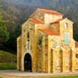 A deux cents mtres de Santa Maria de Naranco se situe l'glise San Miguel de Lillo...L'difice est une glise prromane du IXe sicle (842-850) Elle est classe au patrimoine mondial de l'Unesco..Ramiro 1er la fit construire en mme temps que son palais en tant qu'glise palatine. elle est consacre  Sainte Marie et Saint Michel.   lorigine elle tait de plan basilical  trois nefs, mais on conserve la troisime partie de sa longueur, en effet elle a t probablement dtriore fin du xiiie sicle ou dbut du xive sicle, tant donn les mauvaises qualits du sol. On conserve uniquement le vestibule et le dbut des trois nefs. Au premier plan se trouve la tribune royale et de chaque ct deux petites chapelles.  Elle est vote, par un systme complexe de demi-votes en berceau.  Les nefs sont spars par des arcs qui reposent des colonnes, rendu inhabituel dans la mesure o dans l'art asturien cest le pilier qui est utilis comme support. Ces colonnes s'appuient sur de hautes bases carres qui possdent une dcoration sculpturale qu'encadrent des figures humaines.